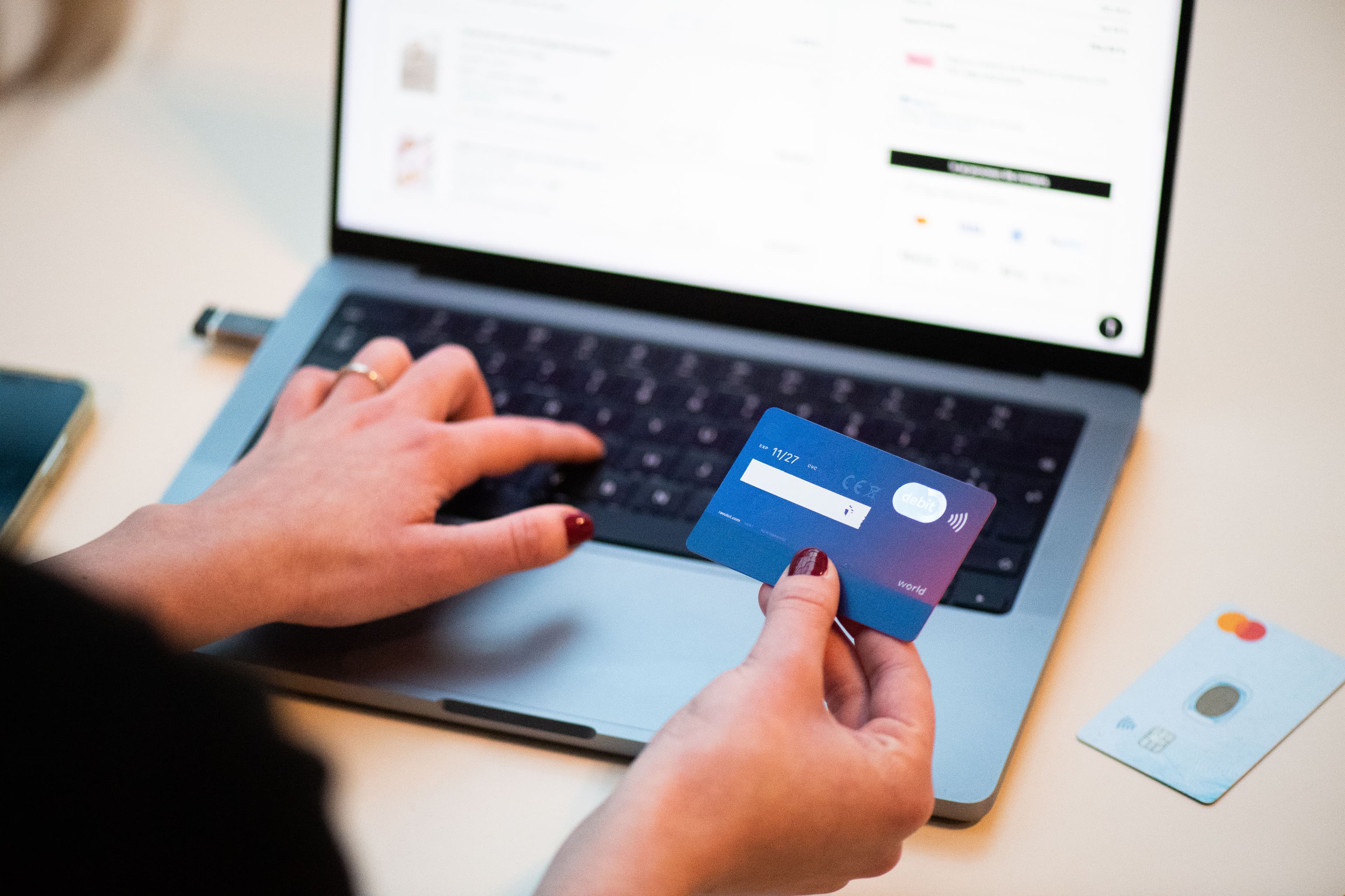 A shopper completing an online purchase on a laptop with a bank card in hand