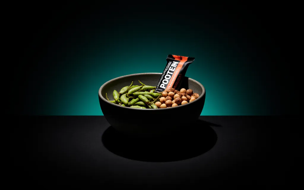 Roasted edamame, chickpeas and a protein snack in a bowl under teal studio light
