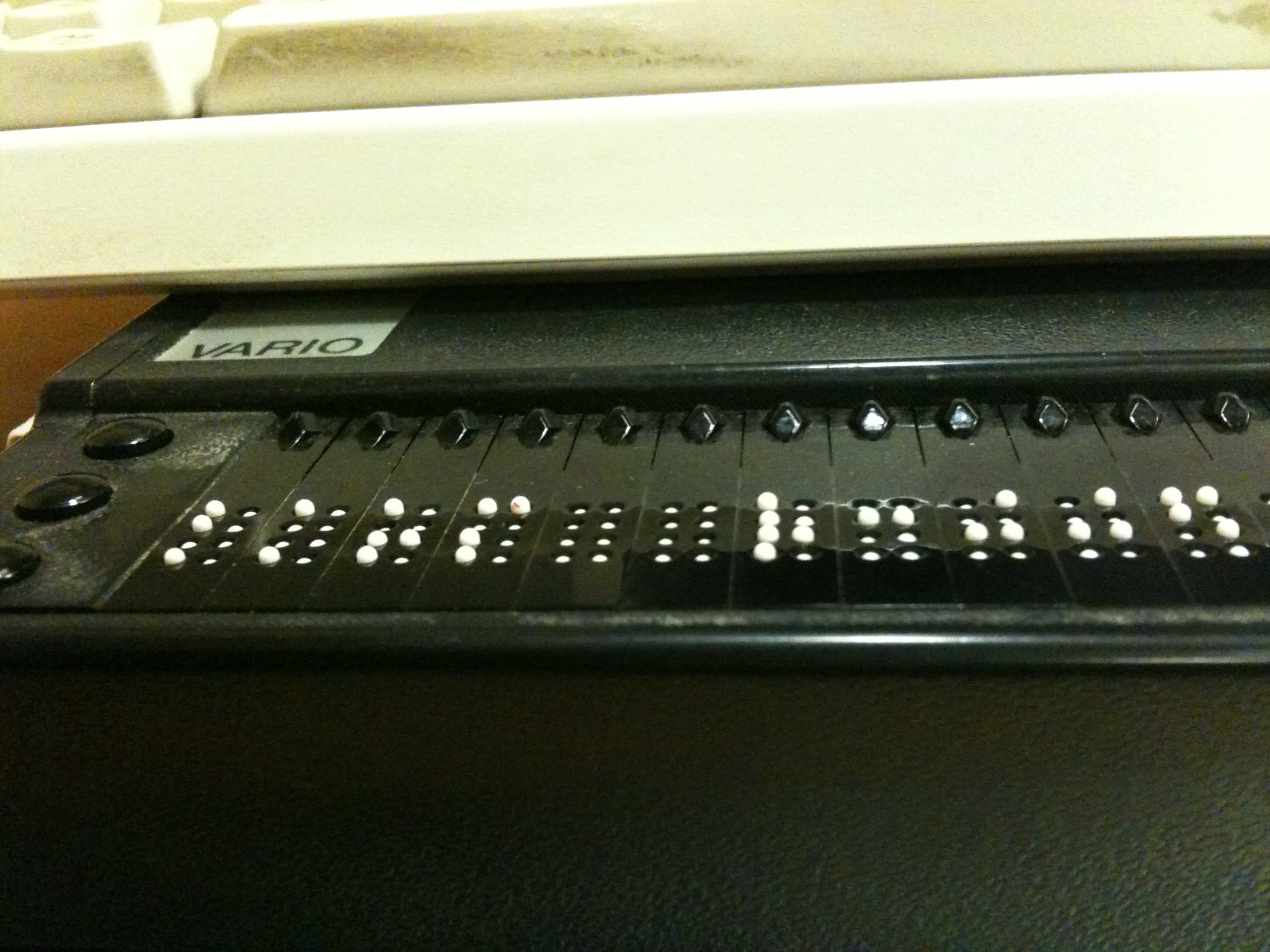 A person reading with a refreshable braille display, the kind of assistive technology overlays often interfere with
